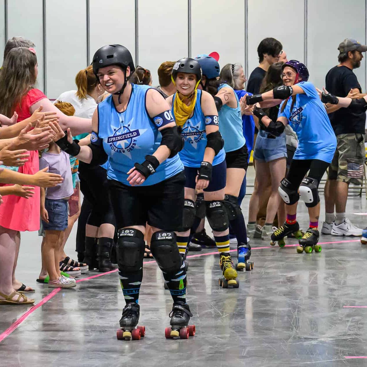 Image of SRD skaters high fiving fans after a bout.